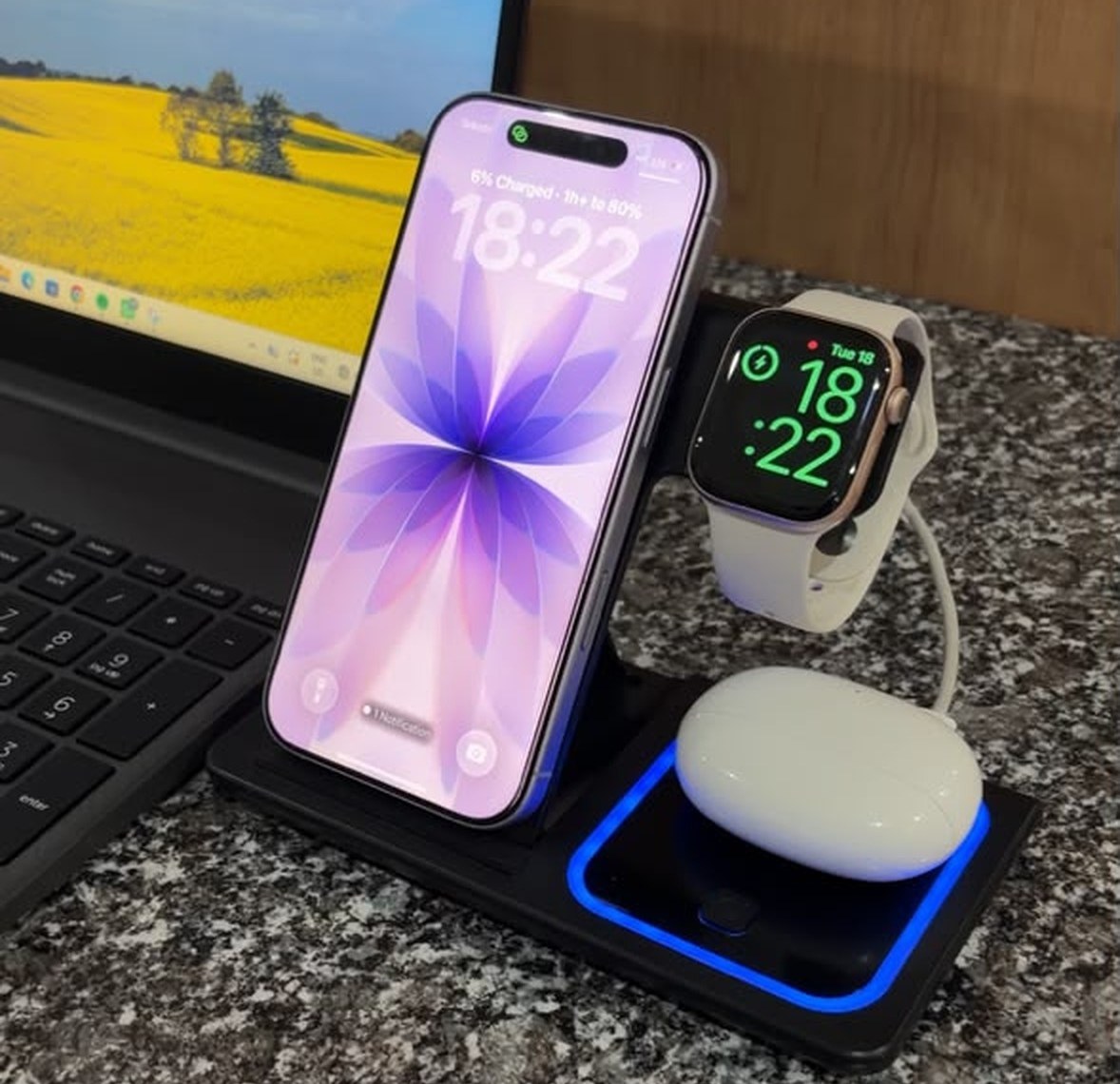 Real photo of the Wireless 3-in-1 Dock charging an iPhone, an Apple Watch and earbuds next to a laptop.